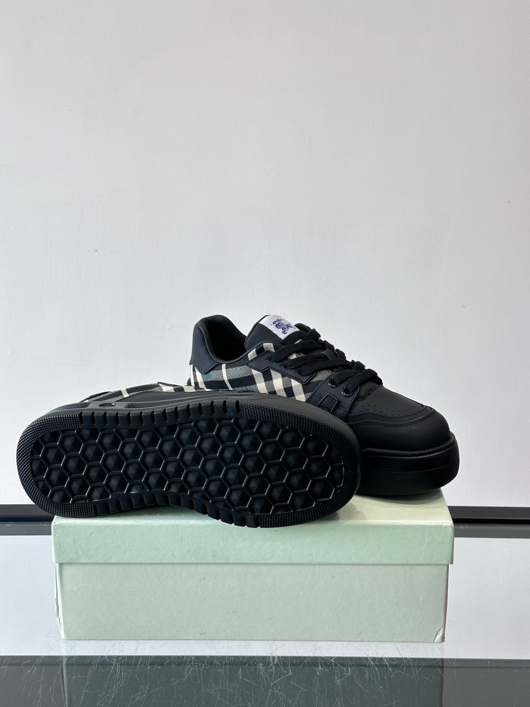 Black sneaker showing tread outsole and check panel side detail