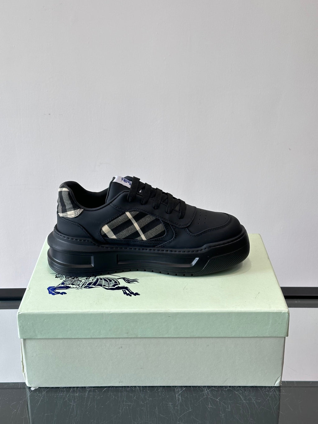 Dark leather low-top sneaker with plaid side accent and black laces