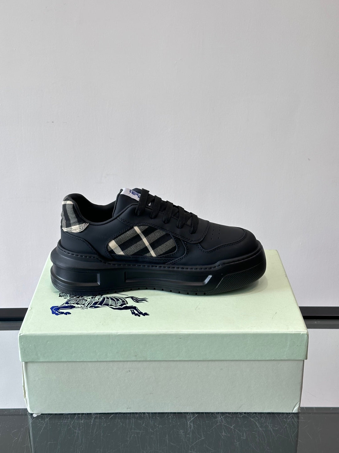 Dark leather low-top sneaker with plaid side accent and black laces