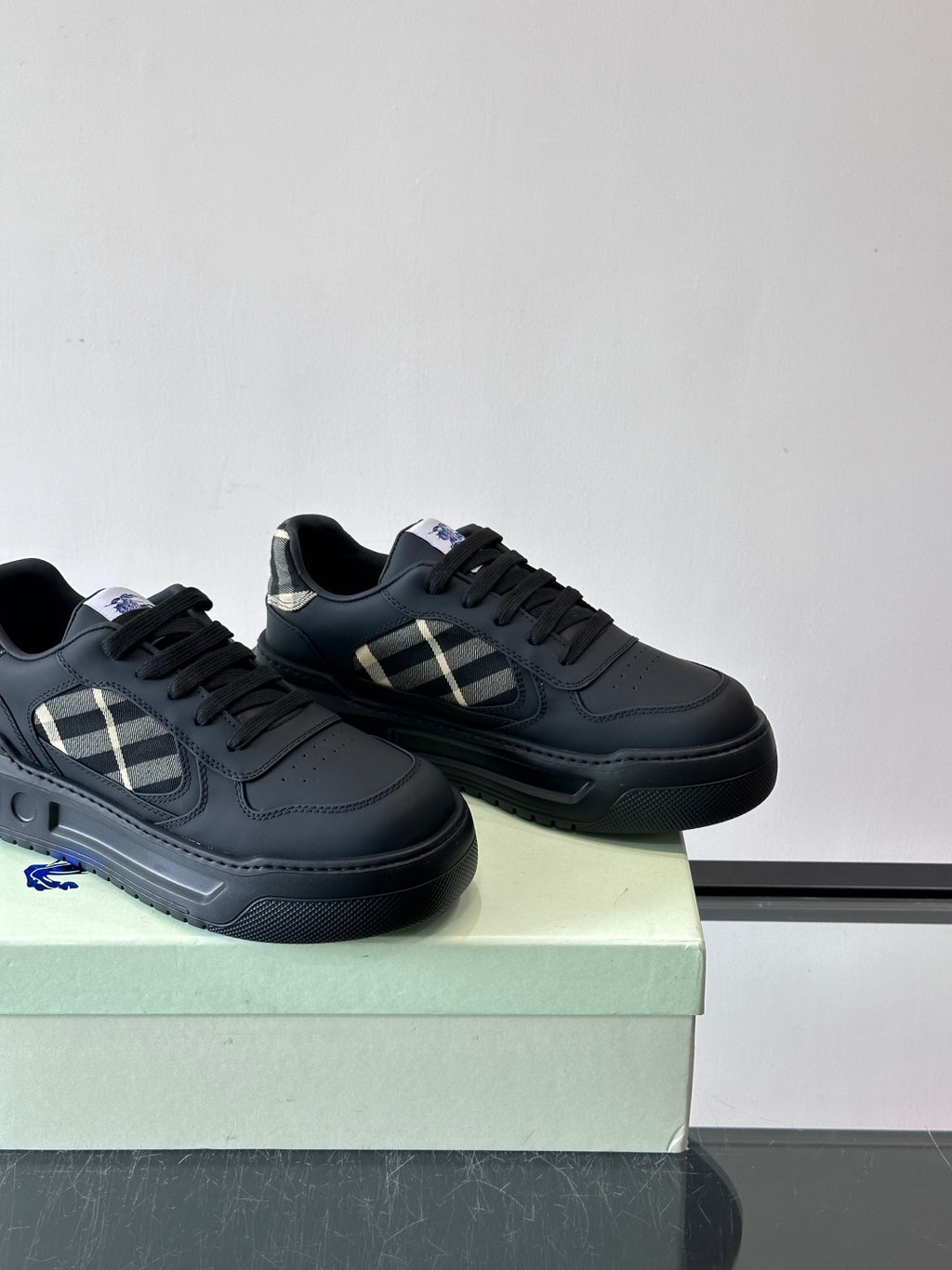 Pair of dark leather low-top sneakers with check panel, black laces, rubber sole