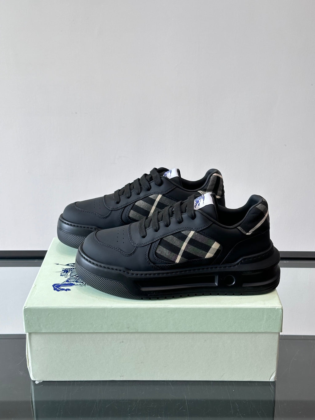 Pair of dark leather low-top sneakers, black laces, plaid logo panel, rubber sole