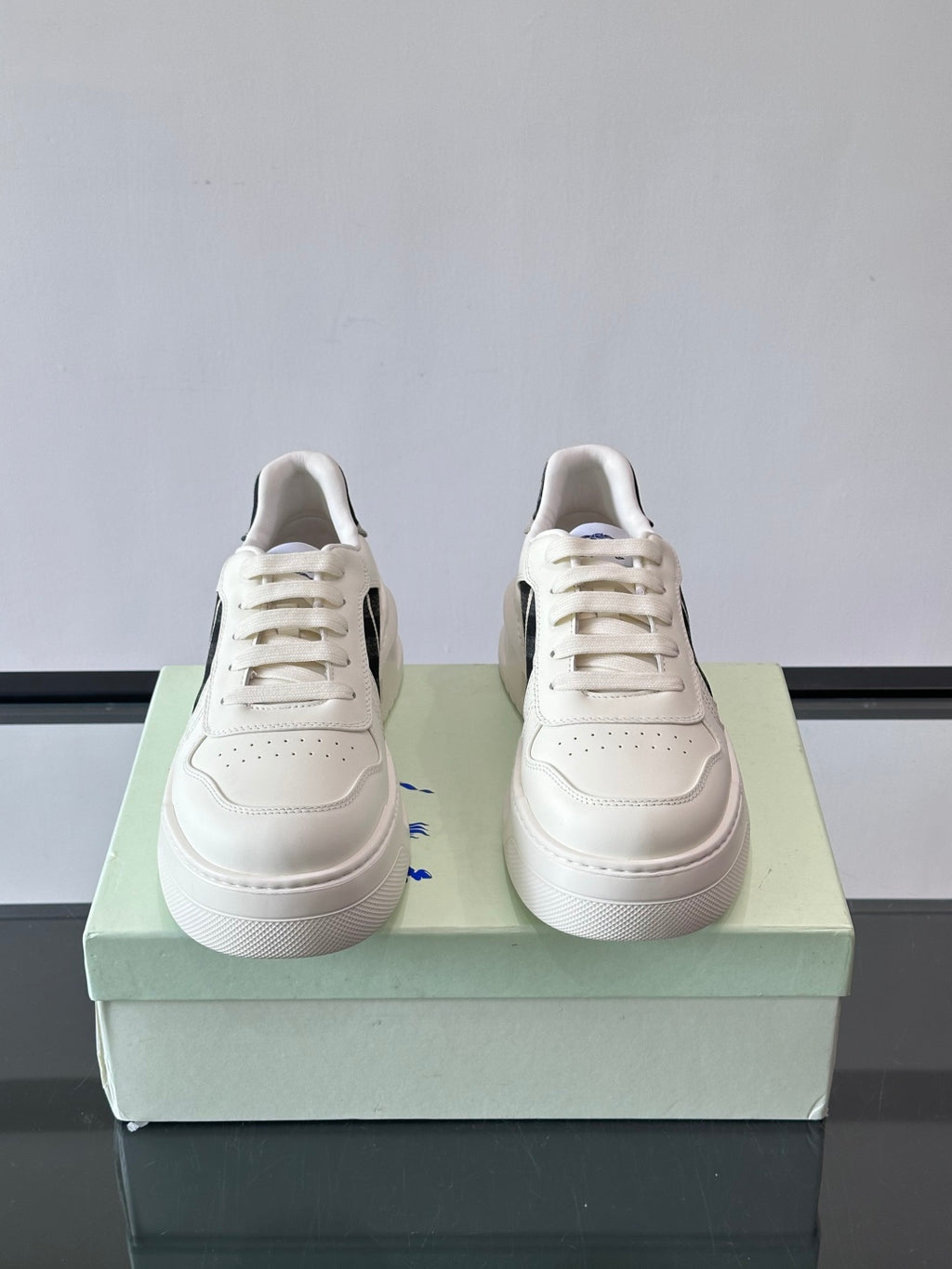 White leather-look sneakers with lace-up front and black plaid side panel