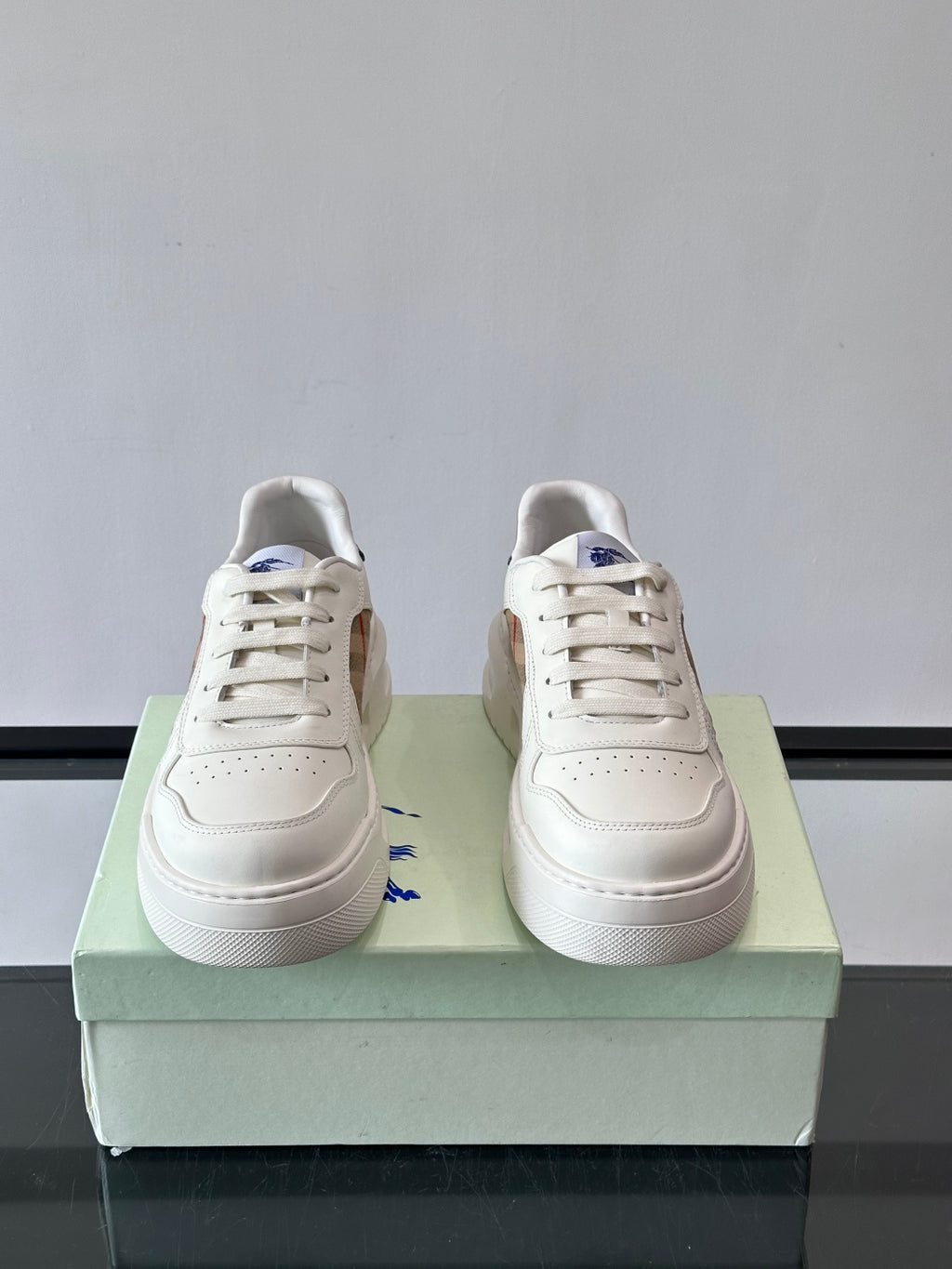 Pair of white lace-up sneakers with perforated toe and flat rubber sole
