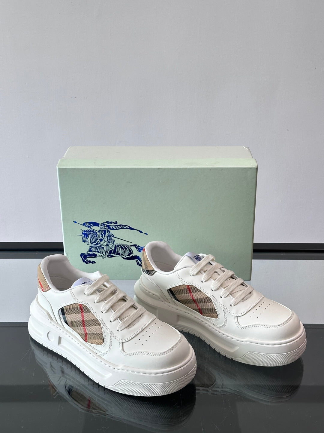 White low-top sneakers with plaid side panels on both shoes, lace-up design