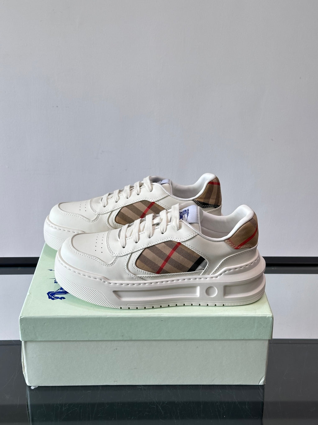 White lace-up sneakers showing plaid side insert and cushioned midsole