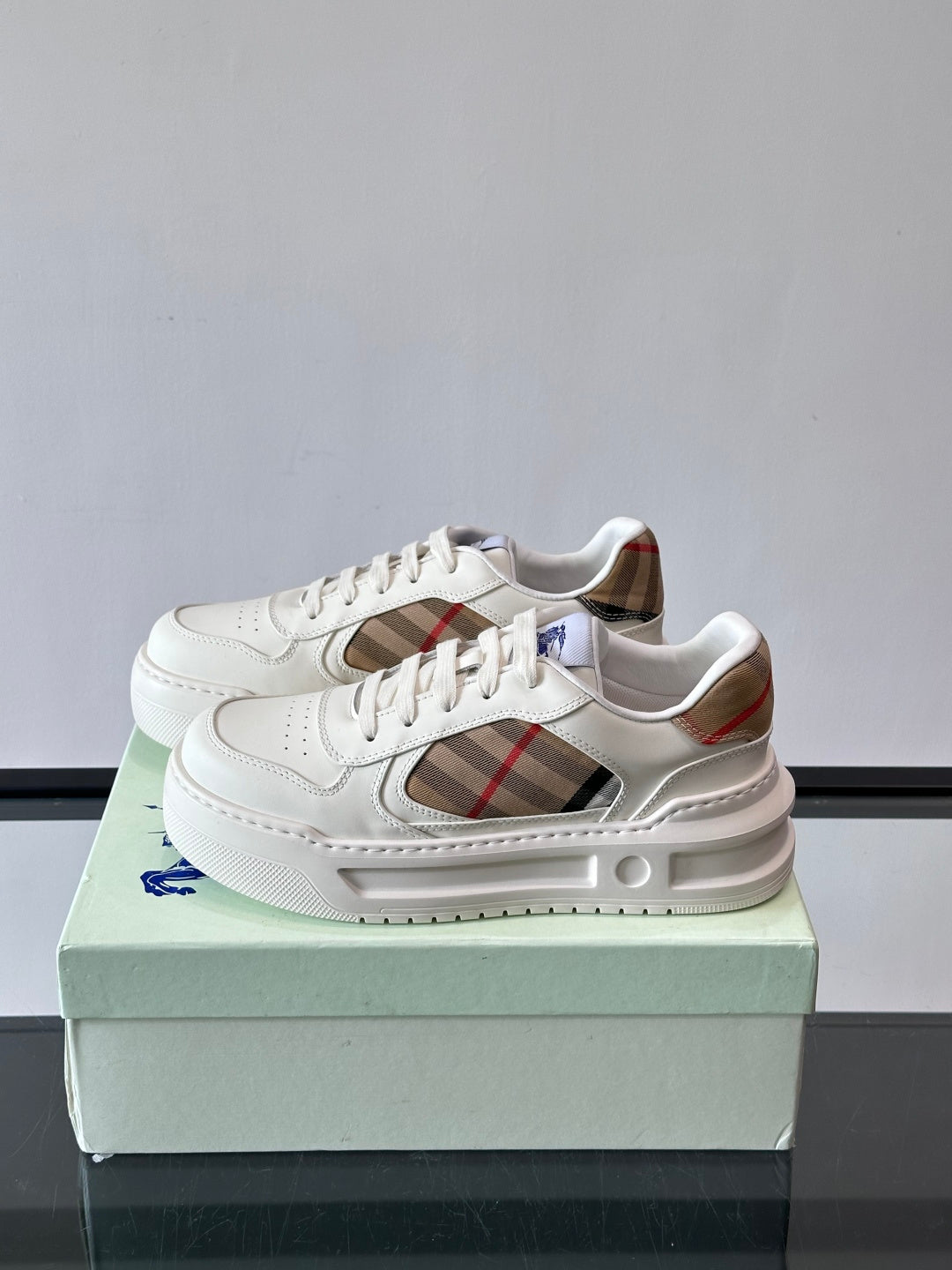 White lace-up sneakers showing plaid side insert and cushioned midsole