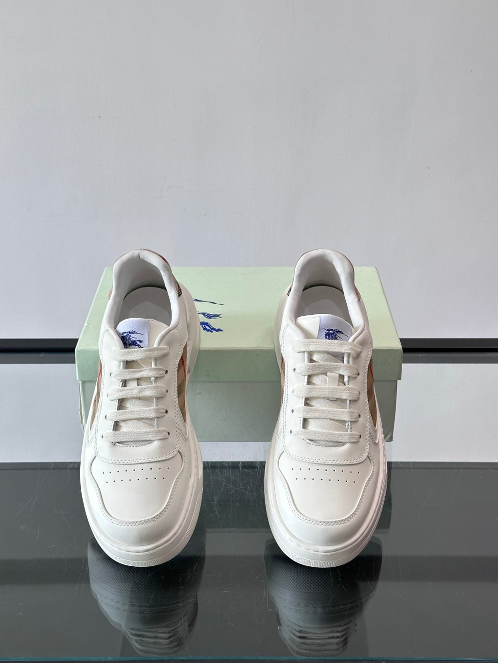 White front view of lace-up sneakers with plaid heel lining and rubber sole