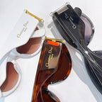 Two cat-eye sunglasses with tinted lenses and accompanying eyewear cases.