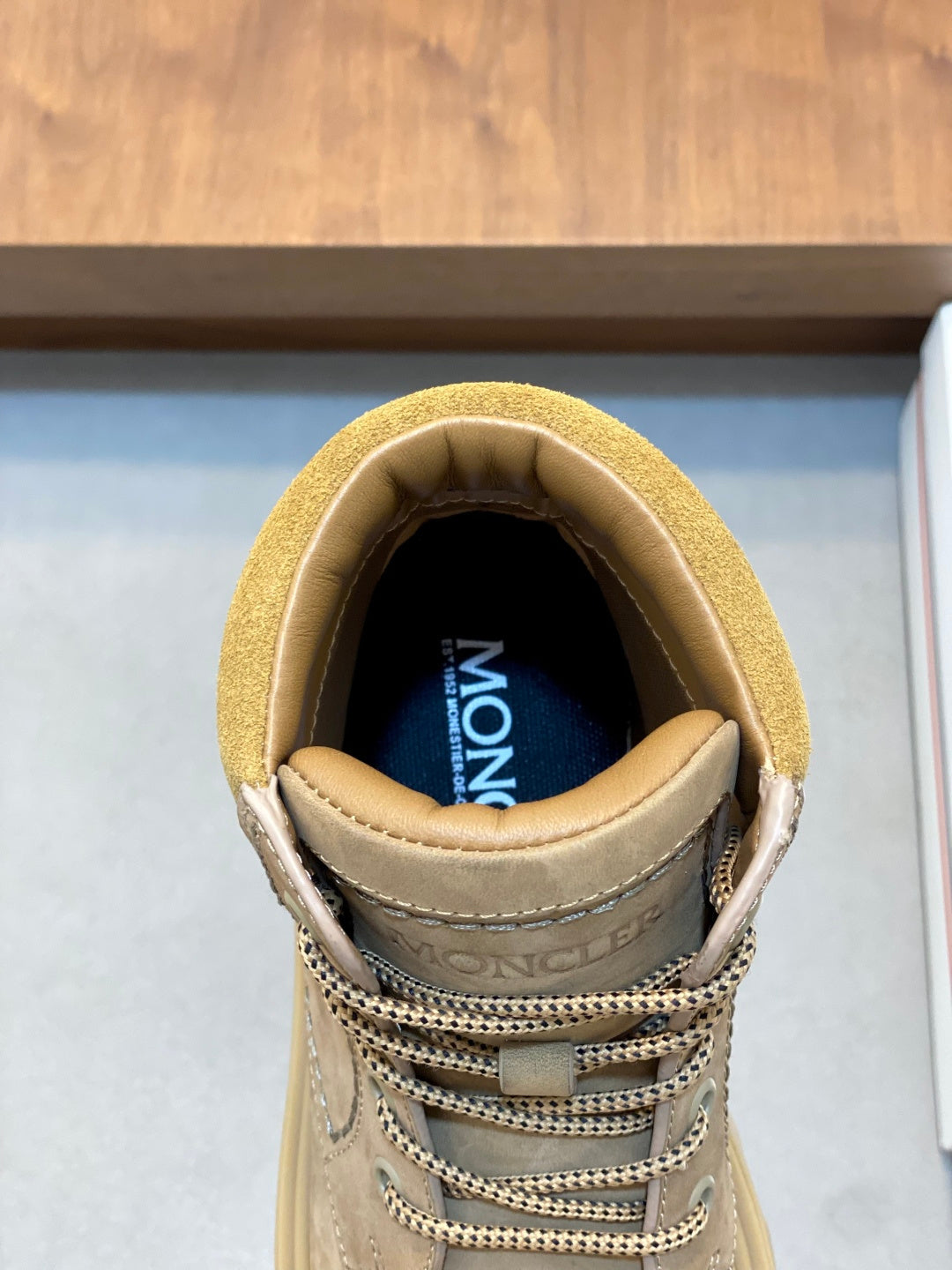 Suede ankle boot showing inner lining with Moncler logo and lace hardware.