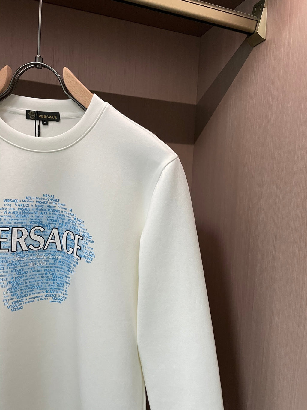 White crewneck sweatshirt showing sleeve and blue Versace graphic detail