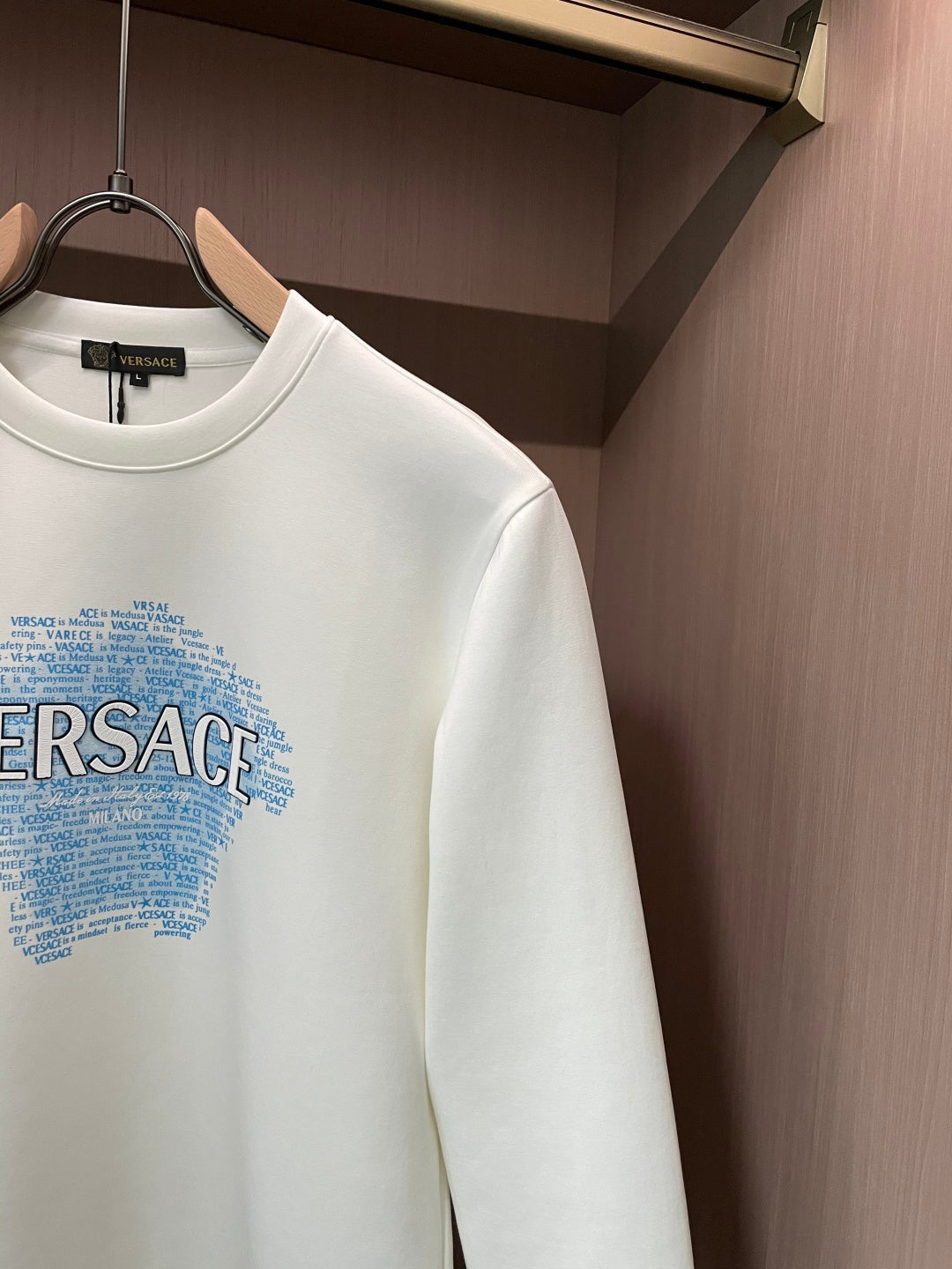 White crewneck sweatshirt showing sleeve and blue Versace graphic detail
