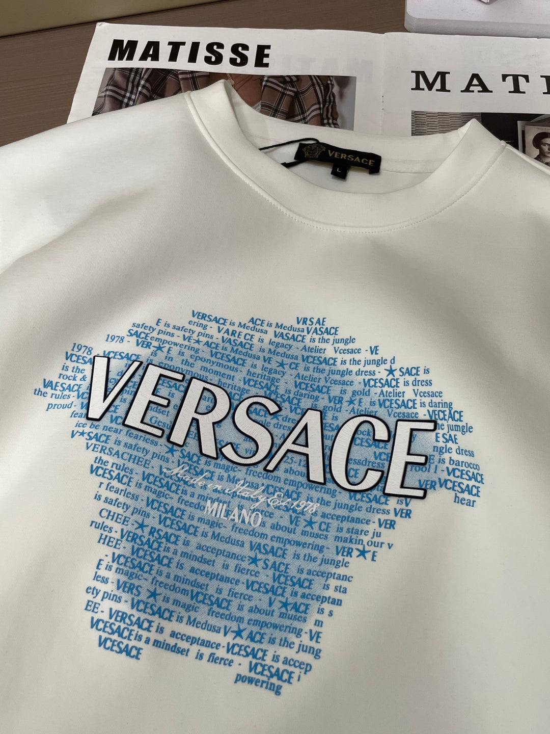 White crewneck sweatshirt with large blue Versace wordmark graphic