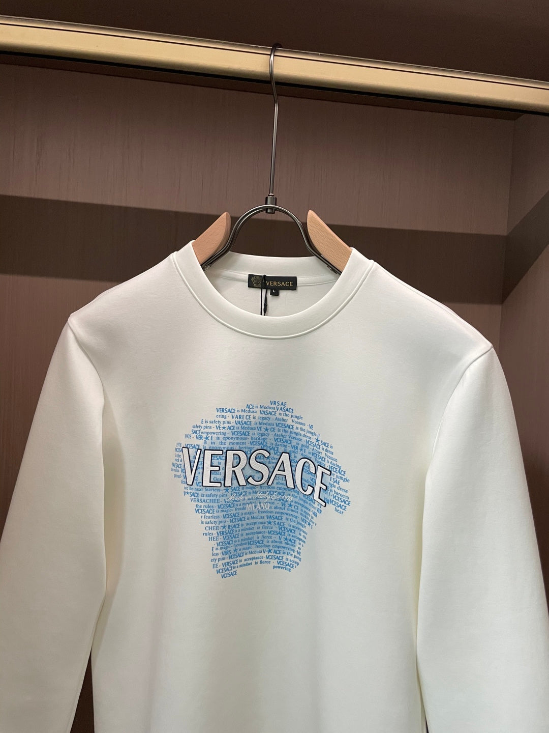 White crewneck sweatshirt with blue Versace graphic, close-up