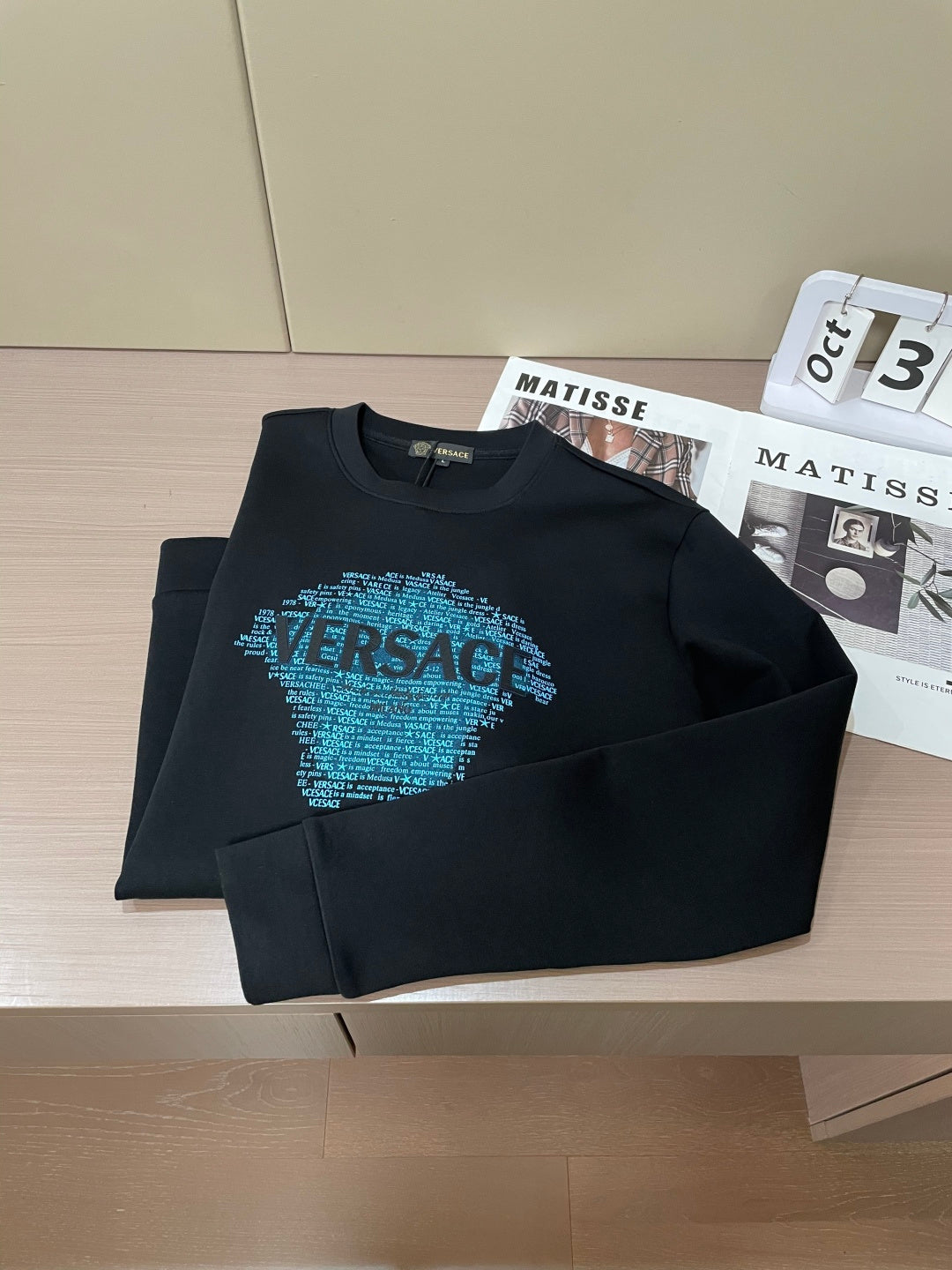Black crewneck sweatshirt folded with blue text face graphic on chest