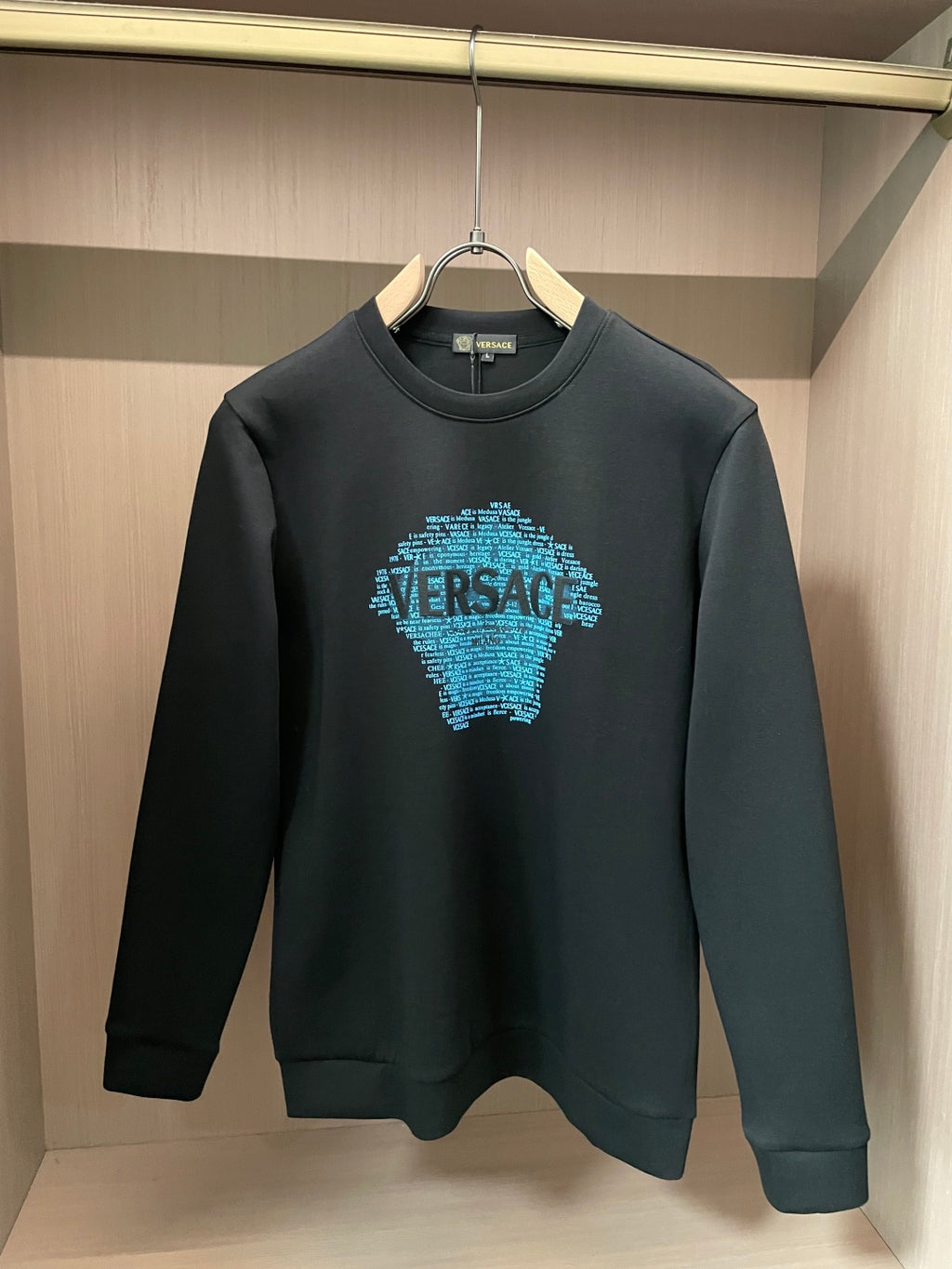 Black crewneck sweatshirt with blue text face graphic on chest