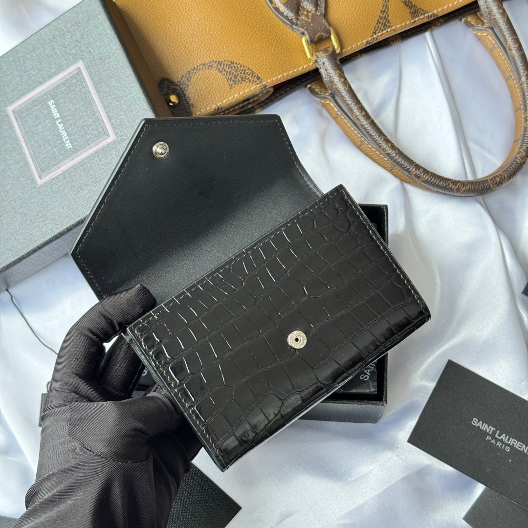 Black small leather bag with croc front panel and top flap, shown in hand