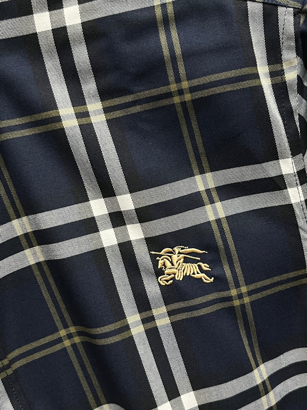 Navy plaid long-sleeve shirt with gold horse logo centered on the front
