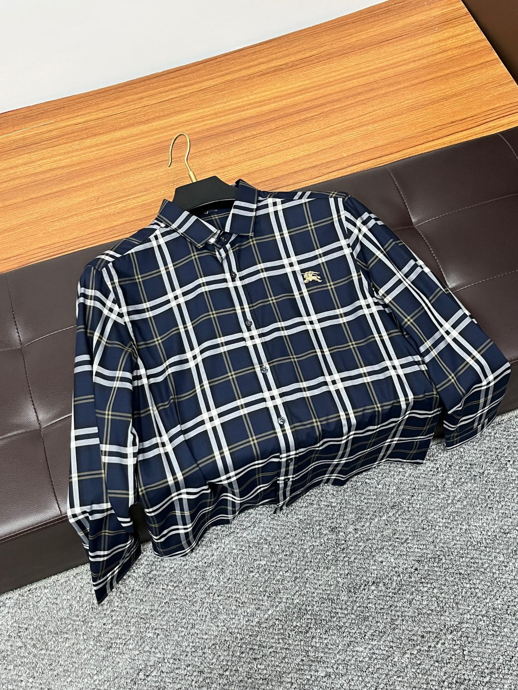 Navy plaid long-sleeve button-up shirt hanging on a wooden hanger