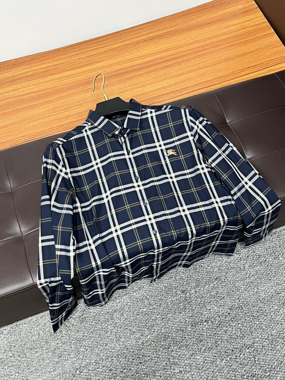 Navy plaid long-sleeve button-up shirt hanging on a wooden hanger