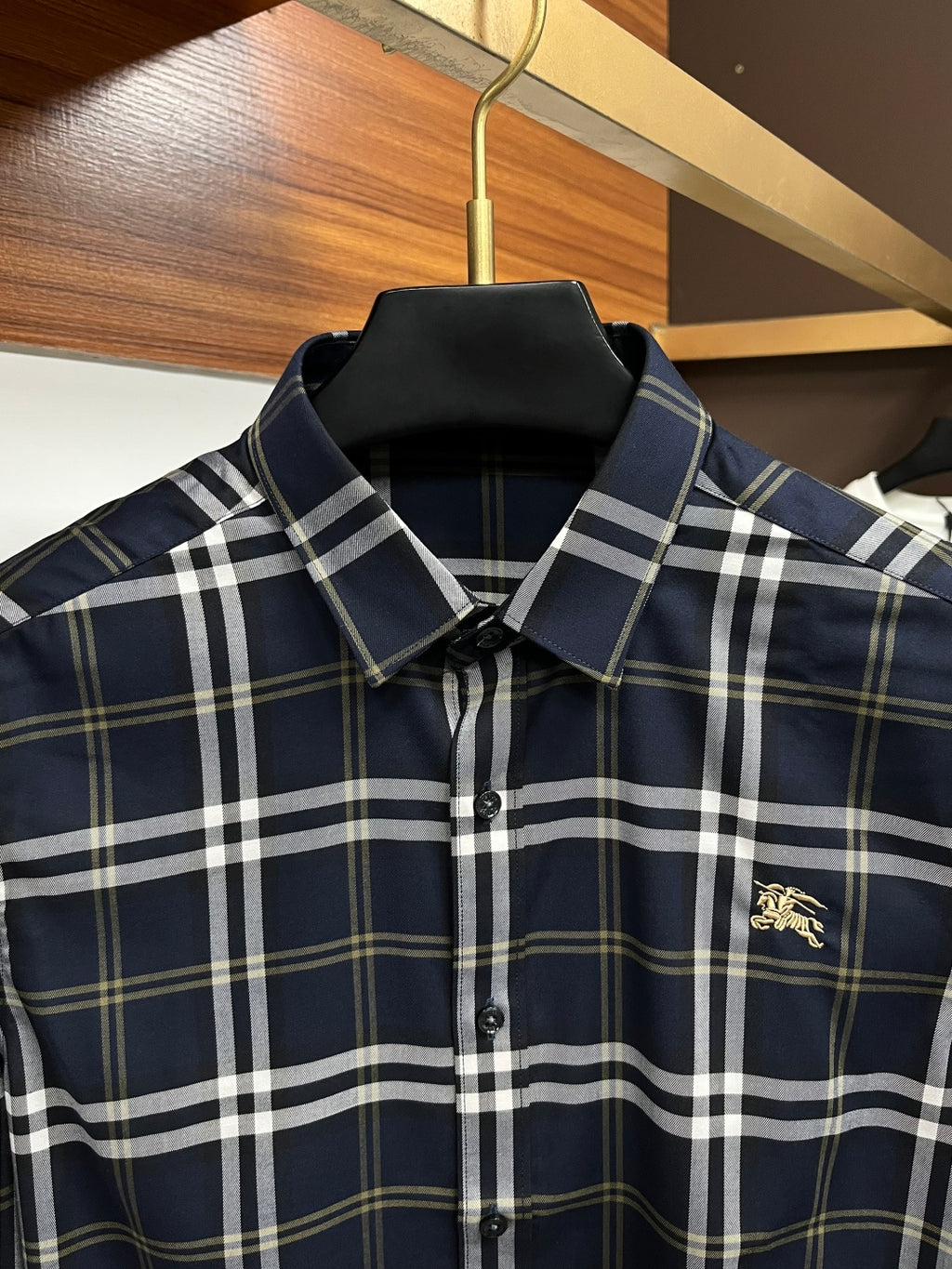 Navy plaid button-up shirt with pointed collar and small gold chest emblem