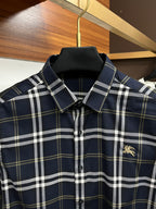 Navy plaid button-up shirt with pointed collar and small gold chest emblem