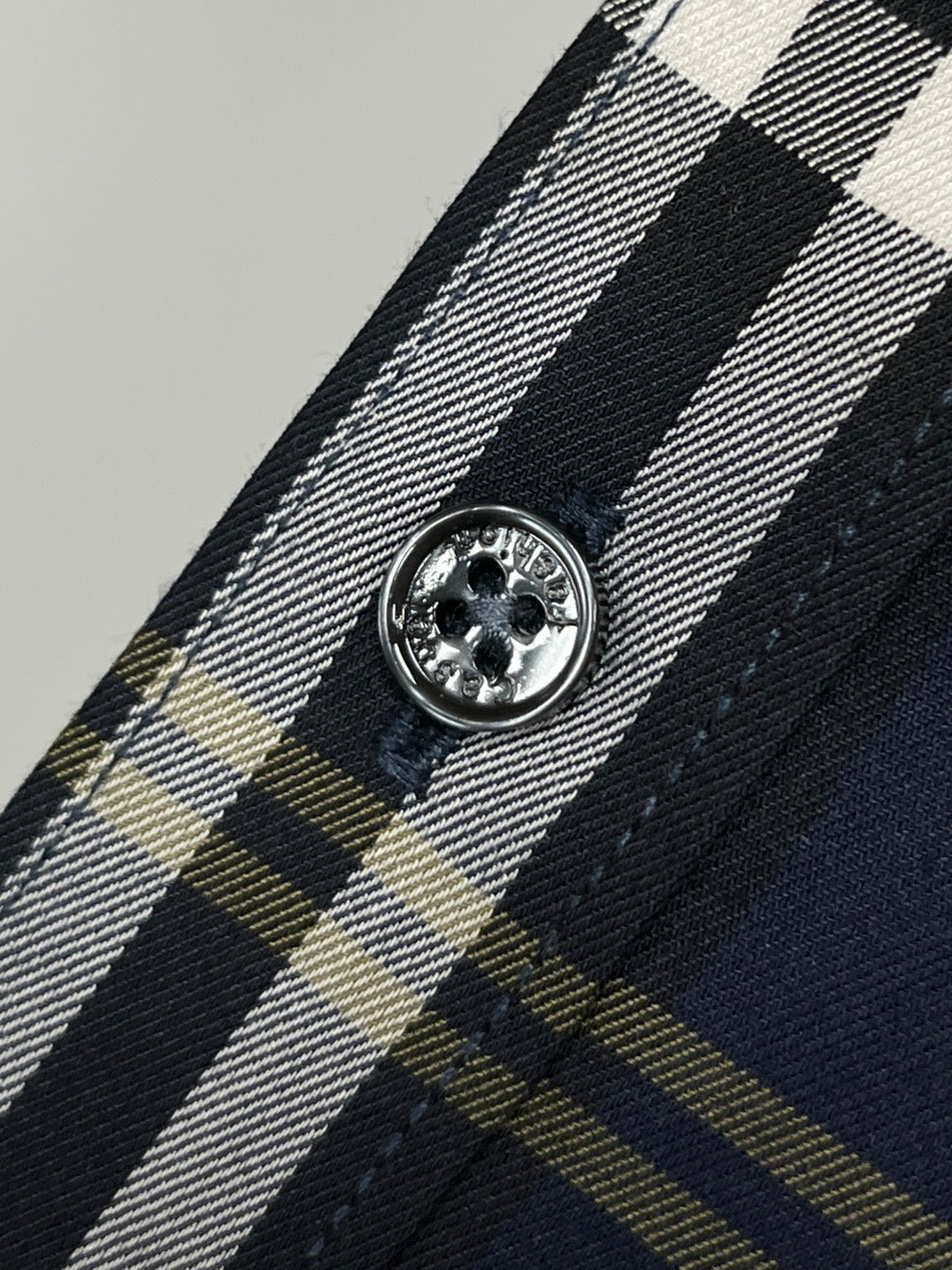 Navy plaid shirt button close-up with round metal-style front button