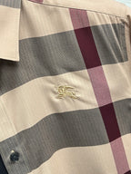 Burberry plaid long-sleeve shirt fabric close-up with gold crest emblem and buttons