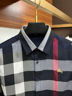 Long-sleeve plaid shirt front close-up in navy, gray, and white with red stripe