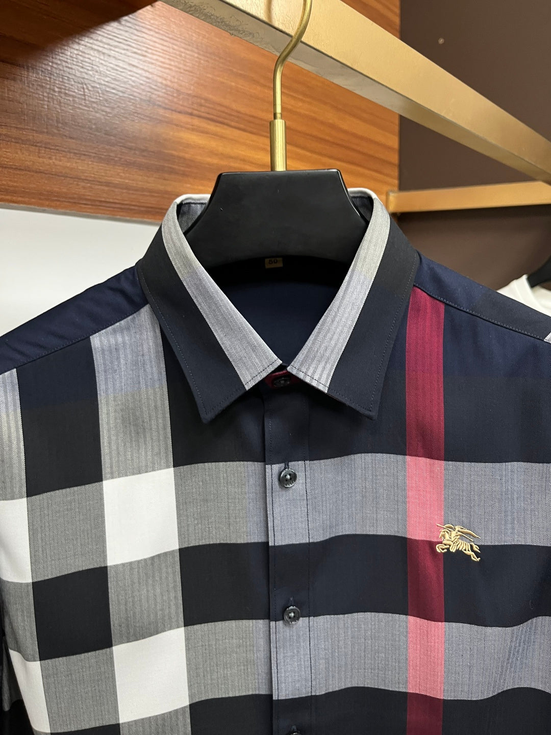 Long-sleeve plaid shirt front close-up in navy, gray, and white with red stripe
