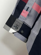 Long-sleeve plaid shirt cuff with dark buttons, navy and gray checks, red accent stripe
