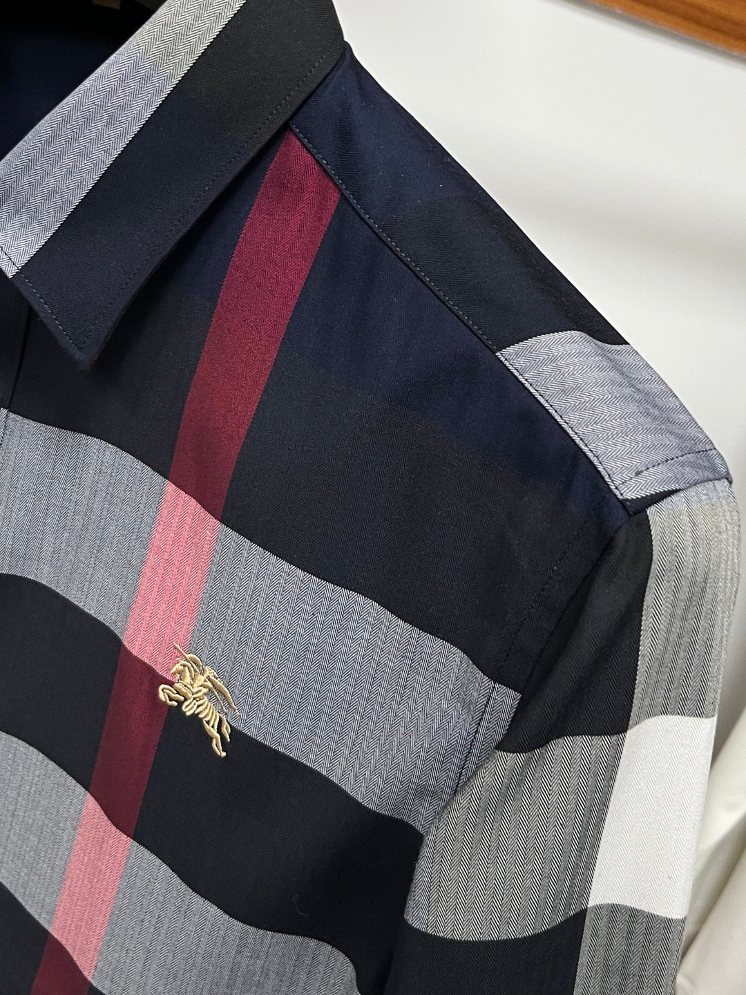 Long-sleeve plaid shirt sleeve with black, gray, and red check and gold logo