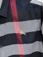 Long-sleeve plaid shirt with gold embroidered emblem on black, gray, and red check