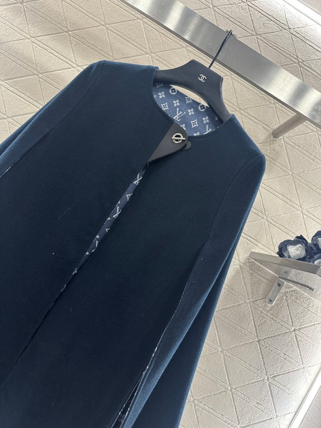 Navy long coat front with stand collar and monogram patterned lining along placket