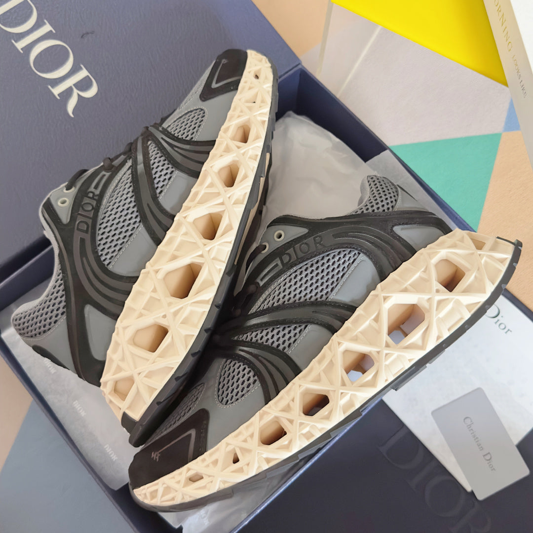 Dior unisex sneaker pair, dark gray mesh with black straps and cream lattice outsole