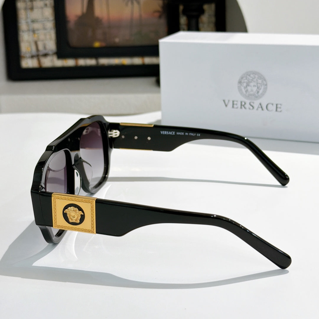 Side view black cat-eye sunglasses with gold logo plaque and tinted lenses