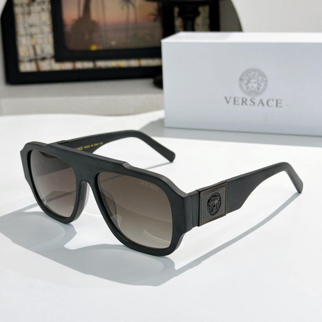 Black cat-eye sunglasses with dark lenses and gold logo plaque on the temple