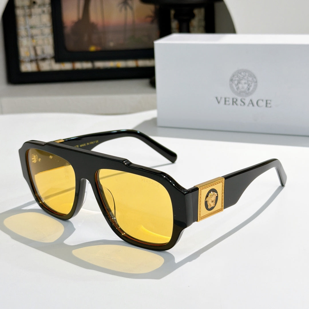 Black cat-eye sunglasses with yellow reflective lenses and gold logo plaque