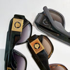 Multiple cat-eye sunglasses with dark frames, gold logo plaques, and tinted lenses
