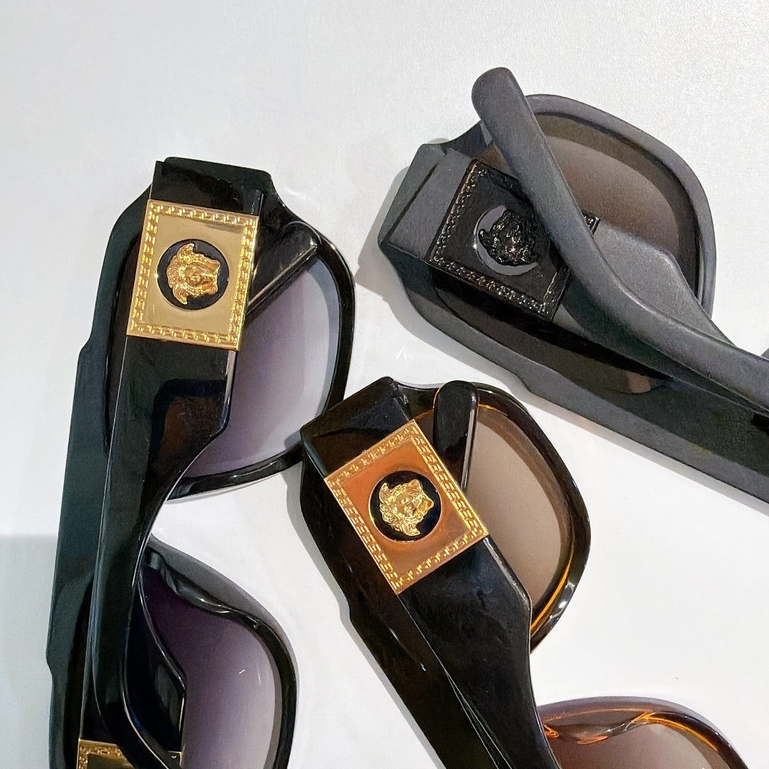 Multiple cat-eye sunglasses with dark frames, gold logo plaques, and tinted lenses