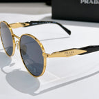 Prada sunglasses with gold metal round frames and blue tinted lenses, side view