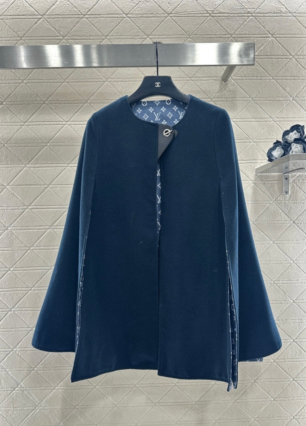 Navy long coat with stand collar and side snap closure, monogram-lined placket
