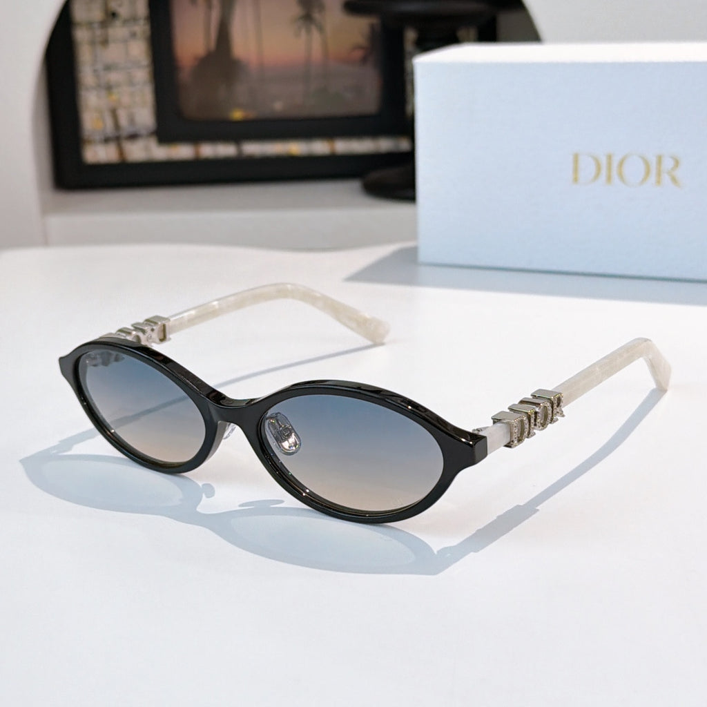 Sunglasses with black frames, clear temples, gold logo detail, dark lenses