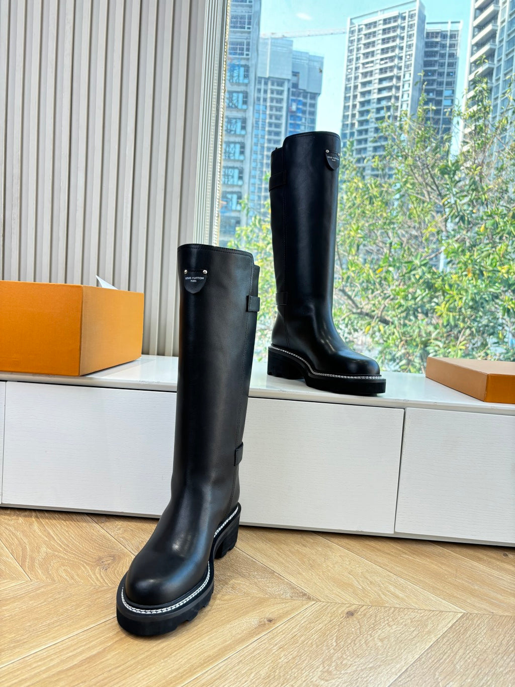 Black leather knee-high boots with buckle and thick tread sole