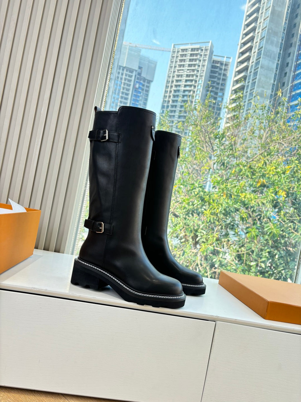 Black knee-high leather boots with buckle strap and stacked low heel