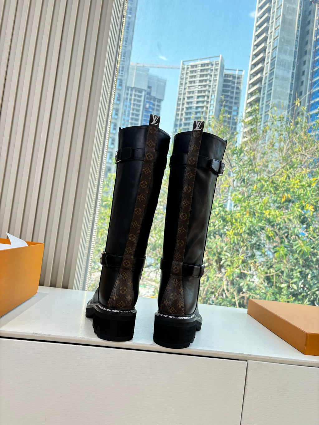 Black knee-high leather boots with patterned panels and side buckles