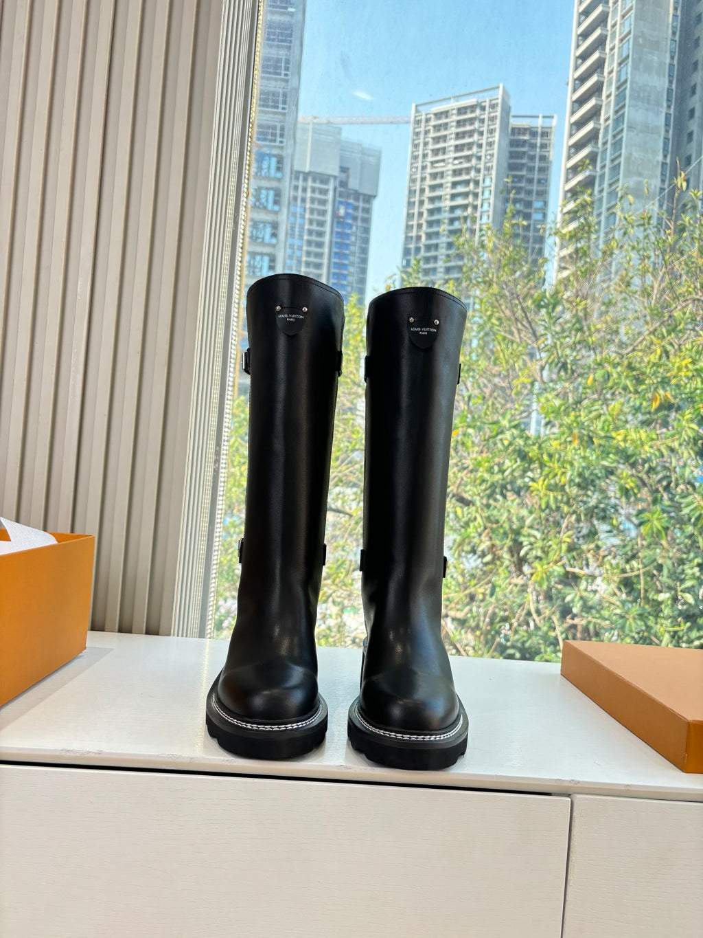 Black knee-high leather boots with side buckles, chunky rubber sole