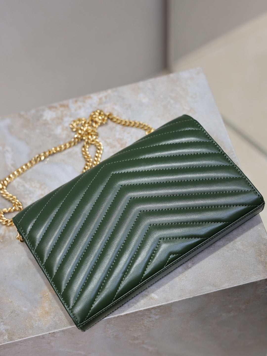 Green quilted leather clutch with YSL logo and gold-tone chain, side/back view.