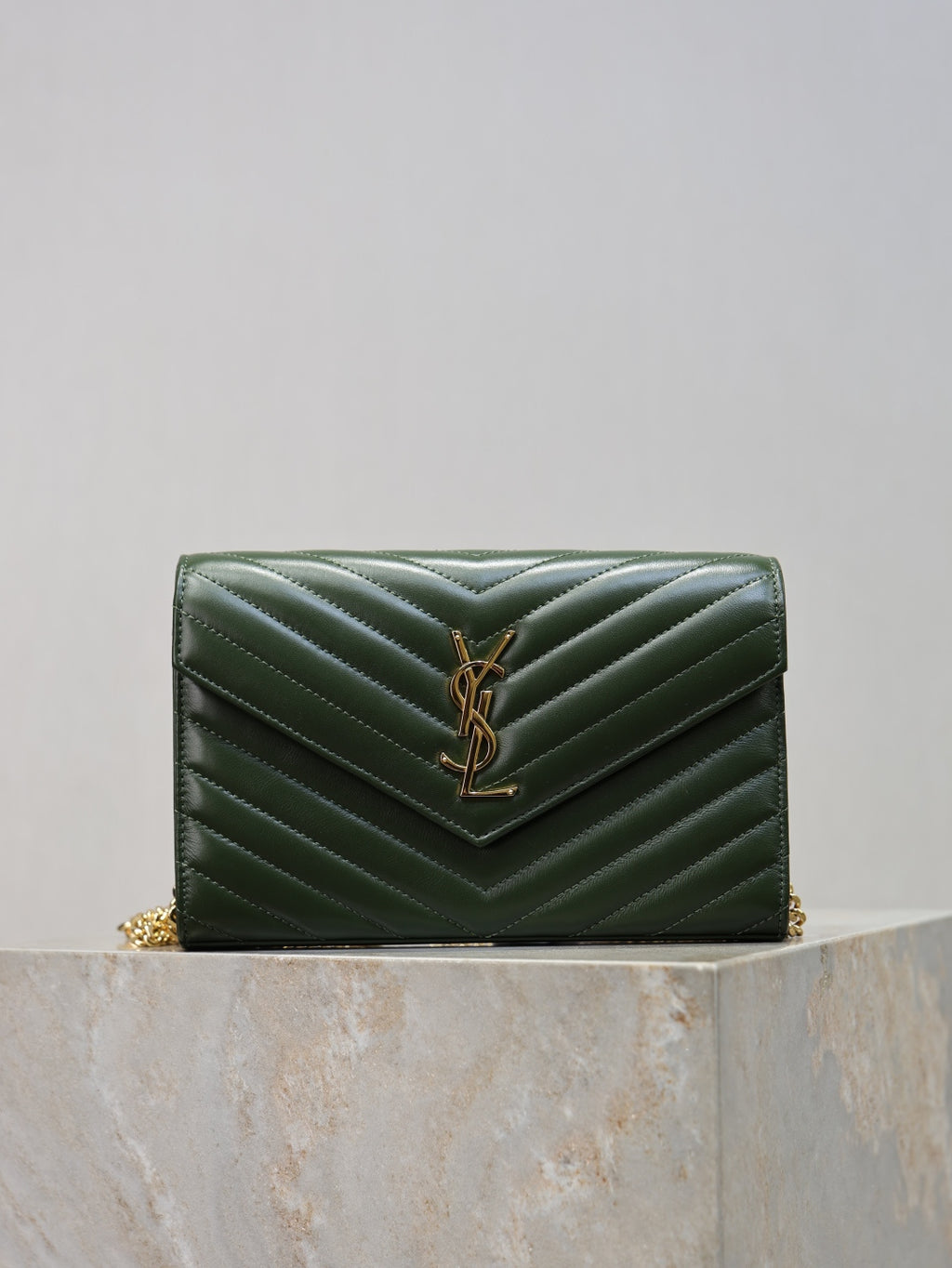 Quilted green leather clutch with YSL logo, chevron stitching, and gold-tone chain strap.