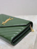 Green quilted leather clutch opened, showing black lining and gold-tone interior hardware.