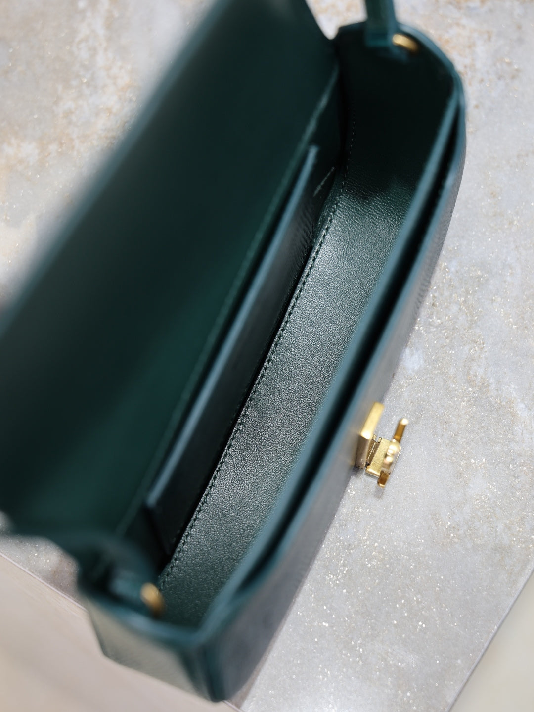 Teal leather handbag interior view with side seam and gold clasp hardware